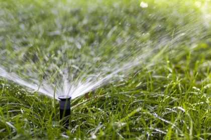Lawn water sprinkler spraying water over grass in garden on a hot summer day. Automatic watering lawns.